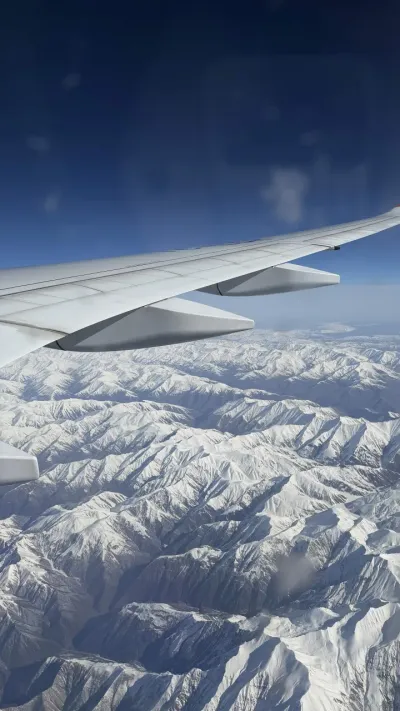 View from an airplane window over snowy mountains