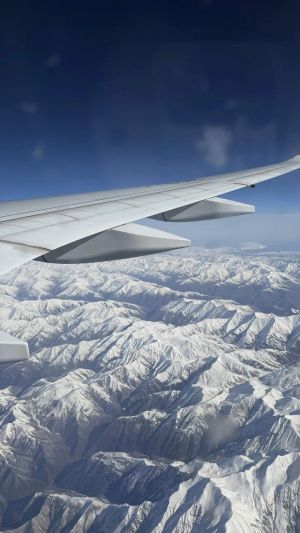 View from an airplane window over snowy mountains